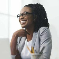 african-american-businesswoman-laughing-sitting-against-window-in-office-e1631573683612.jpg